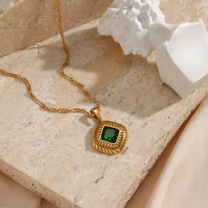 Detailed close-up of a vintage golden rope chain necklace with a green zircon pendant
