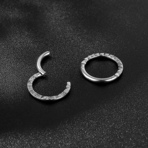 Titanium steel hinged nose rings with pyramid pattern engraving on black background