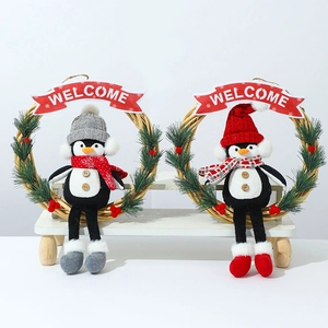 Christmas penguin wreath with red and grey knitted dolls on a wooden decorative bench