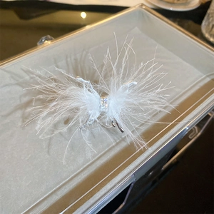 Close-up of white feather butterfly accessory with sparkling crystals on silver base