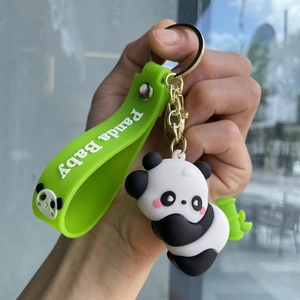 Close-up of cute panda keychain with green silicone strap and golden metal ring