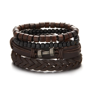 Detail of stacked dark brown braided leather bracelets set with black wooden beads and dumbbell charm