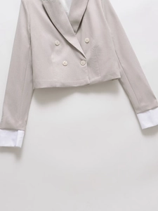 Detail of short grey blazer with double-breasted buttons and white cuff layering
