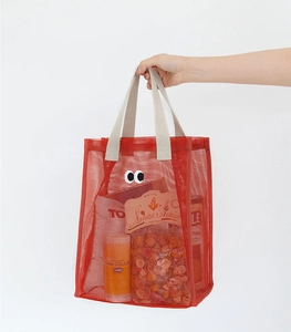 Detail of red mesh beach bag with cartoon eyes and beige canvas handles