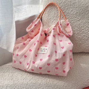 Detail of pink canvas tote bag with red heart patterns and orange woven rope handles