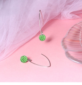 Detailed view of silver hook earrings with sparkling green rhinestone pave ball pendants