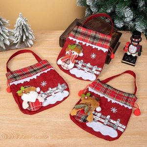 Christmas gift bags with Santa, snowman, and reindeer designs on light wood surface