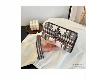 Close-up of geometric pattern long wallet with wrist strap and gold zipper details