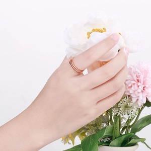 Detail of rose gold triple-layer spiral ring with paved crystals on model's finger