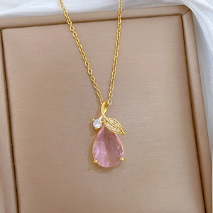Gros plan d'un pendentif en cristal rose en forme de goutte avec feuille dorée