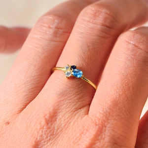 Elegant gold ring featuring blue and white zircon gemstones on a slim minimalist band