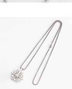 Detail of a rotating silver snowflake pendant with small diamonds on a box chain necklace
