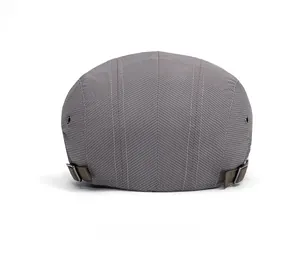 Detail of grey herringbone flat cap with adjustable brown straps and silver metal buckles