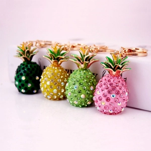 Creative rhinestone pineapple keychain in four vibrant colors on a pink background