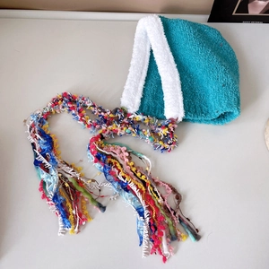 Close-up of blue plush trapper hat with white faux fur trim and colorful long tassels