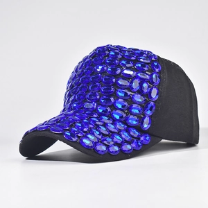 Dettaglio di un berretto da baseball nero decorato con grandi strass blu ovali sul davanti