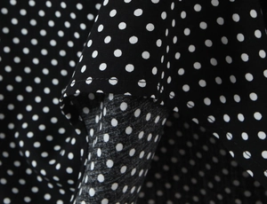 Detailed close-up of white polka dot print on black fabric with fine stitching quality