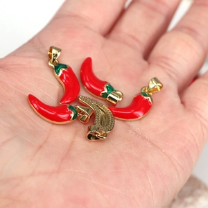 Red and green enamel chili pepper pendants for DIY jewelry making shown in hand