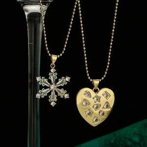 Gold plated snowflake and heart pendant necklaces with zircon crystals on elegant background