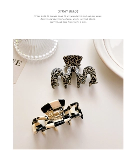 Detail of tortoise shell and checkerboard pattern hair claw clips on a minimalist background