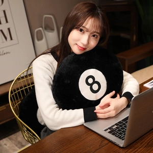 Detail of creative black eight billiard plush pillow held by a model in a cozy setting
