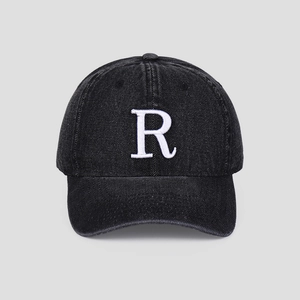 Détail du logo R blanc brodé en 3D sur une casquette en denim noir délavé vintage