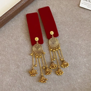 Detailed close-up of ethnic gold-plated tassel earrings with bells on red display cards