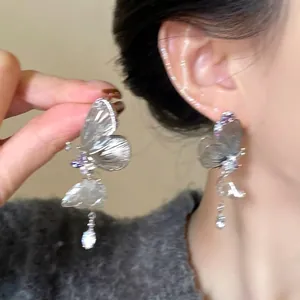 Detail of butterfly drop earrings featuring shimmering crystals and purple stones