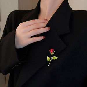 Detail of red enamel rose brooch pinned on a black suit lapel for elegant styling