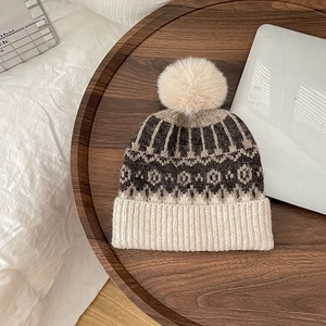 Detailed knit texture of children's geometric wool hat with soft pompom on wood