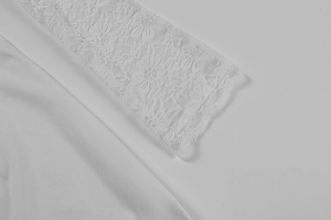 Detail shot of the delicate white floral lace patchwork on the long dress sleeve