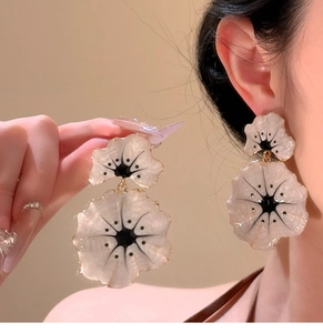 Detailed view of pearlescent ginkgo flower earrings with gold finish on a model