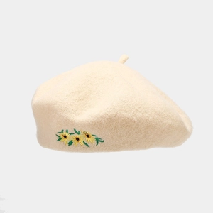 Detail of embroidered yellow flowers on an oatmeal wool beret with a classic top stem