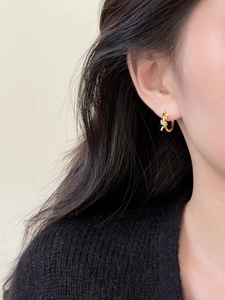 Gros plan de boucle d'oreille créole nouée plaquée or avec zircons sur modèle