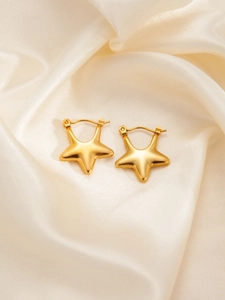 Macro shot of gold star-shaped earrings featuring 3D puffed design and smooth metal texture