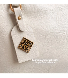 Detailed close-up of white lychee pattern leather tote with vintage gold metal charm