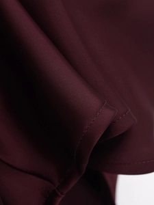 Macro shot of burgundy satin fabric showing premium texture and fine double-needle stitching