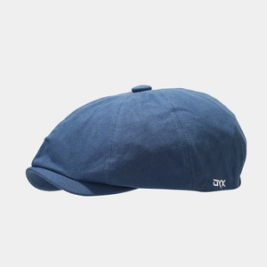 Detailed shot of a dark blue newsboy cap with textured fabric and white JYX embroidery