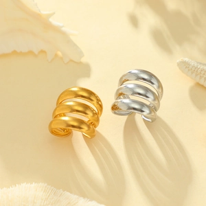 Minimalistische Ear Cuffs in Gold und Silber auf maritimem Hintergrund mit Wellenform