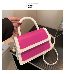 Detail of contrast color handbag in rose red and white with top handle and strap