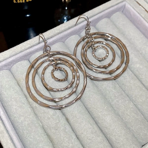 Detail of silver textured multi-layered geometric circular drop earrings in a velvet tray