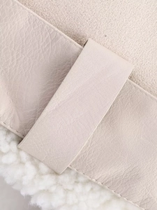 Detail of off-white faux leather jacket with plush shearling trim and fine stitching