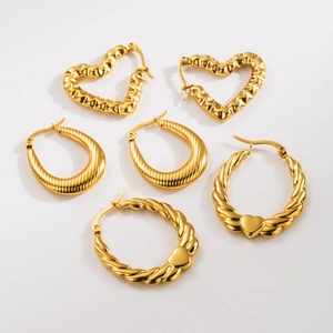 Three gold stainless steel earrings with heart charms and twisted textures on a white surface