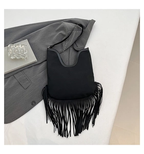 Close-up of black fringe tassel tote bag with U-shaped opening on a grey blazer