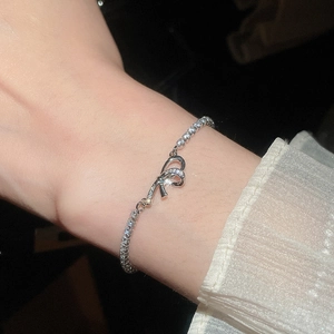 Close-up of silver bow bracelet with pavé-set zircon crystals on elegant wrist