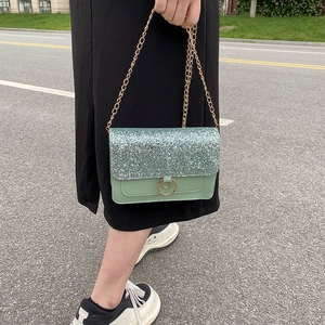 Mint green sequin crossbody bag with gold chain strap shown in an outdoor street setting