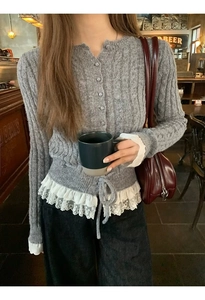 Detail of grey cable knit cardigan featuring delicate white lace trim and drawstring waist