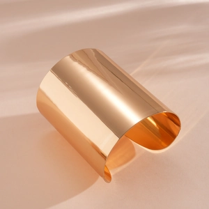 Nahaufnahme eines breiten, polierten goldene Armreifs mit glattem Spiegel-Finish.