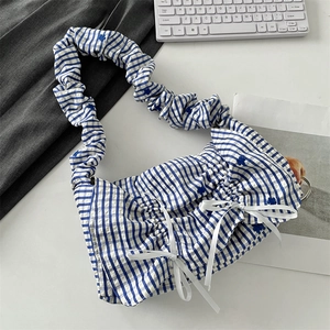 Macro detail of blue and white checkered fabric with delicate floral embroidery and ribbon