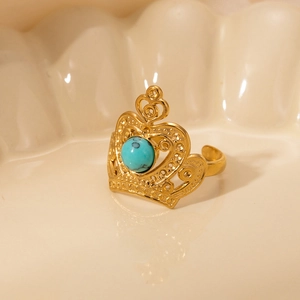 Detailed macro of golden crown ring with turquoise stone inlay on ceramic dish